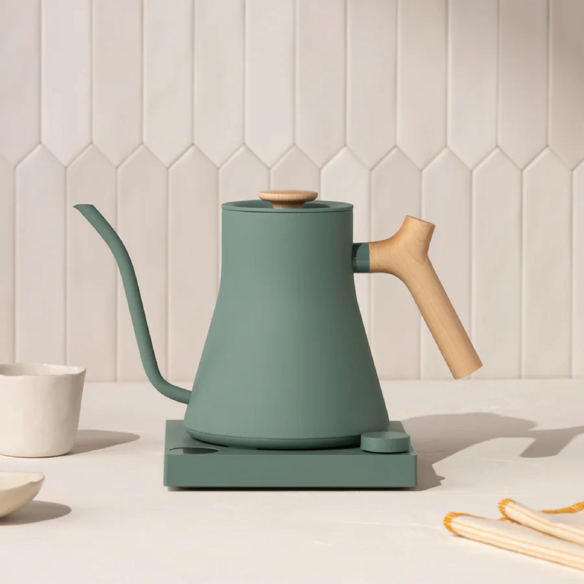 Fellow Stagg EKG Electric Kettle Smoke Green with wooden handle and precision pour spout on a white countertop